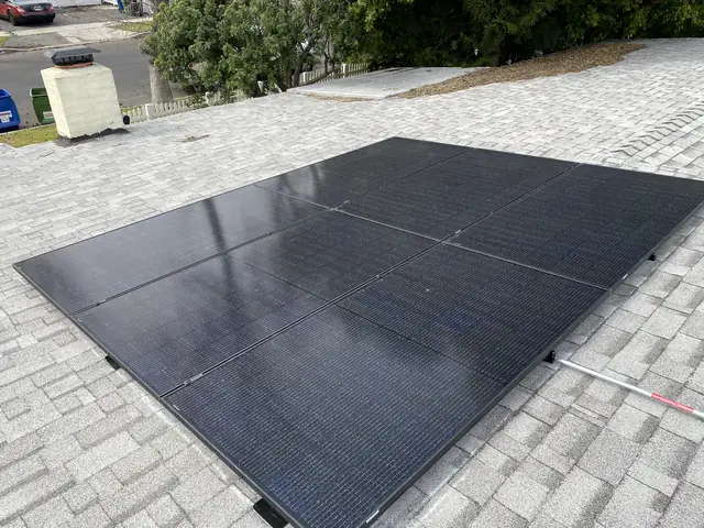 Black solar modules laid across a grey composition shingle roof, North Hollywood