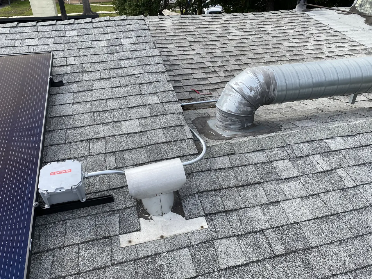 Module edge, roof junction box and a large galvanised duct on a shingle roof, North Hollywood