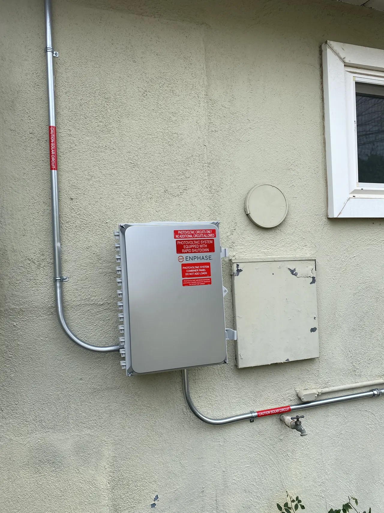 Solar combiner and a closed enclosure mounted on an exterior stucco wall, North Hollywood