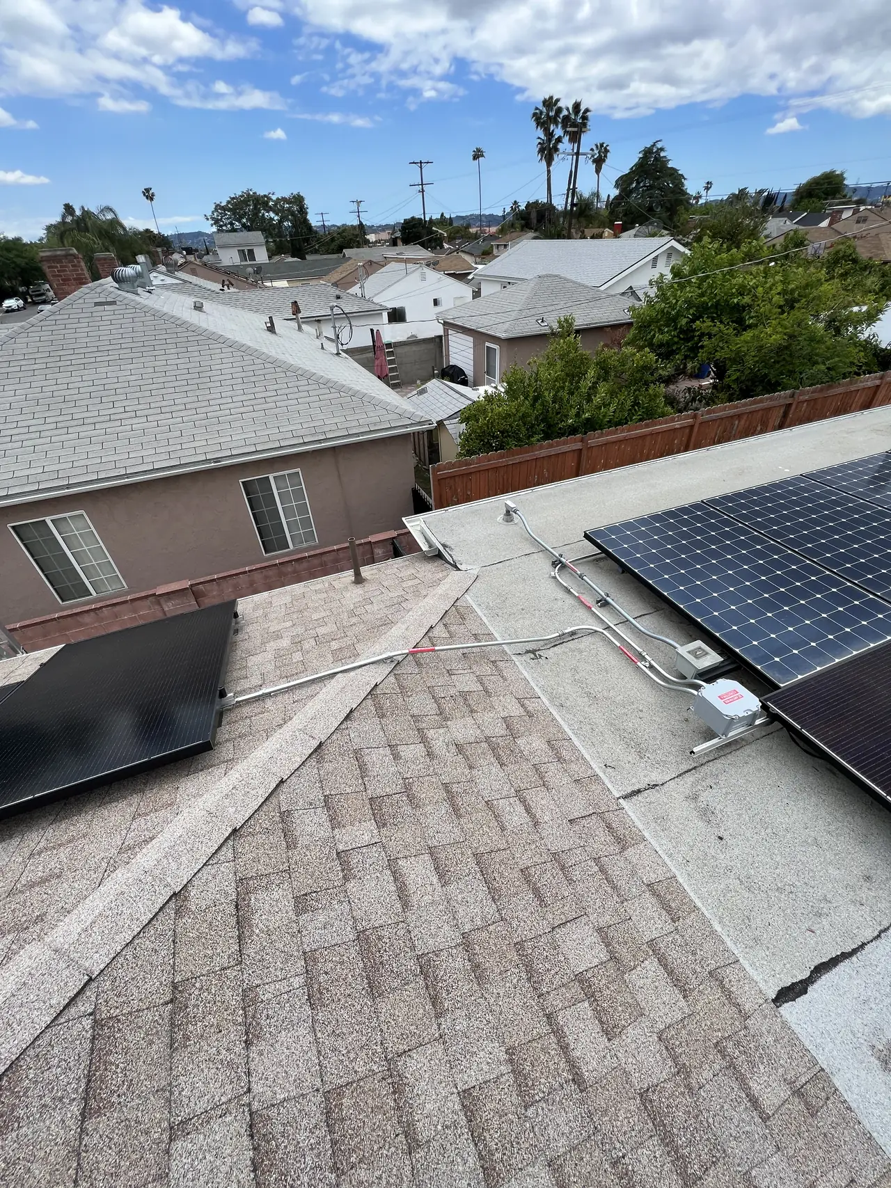 Two separate solar arrays on adjacent roof planes with houses beyond, North Hollywood