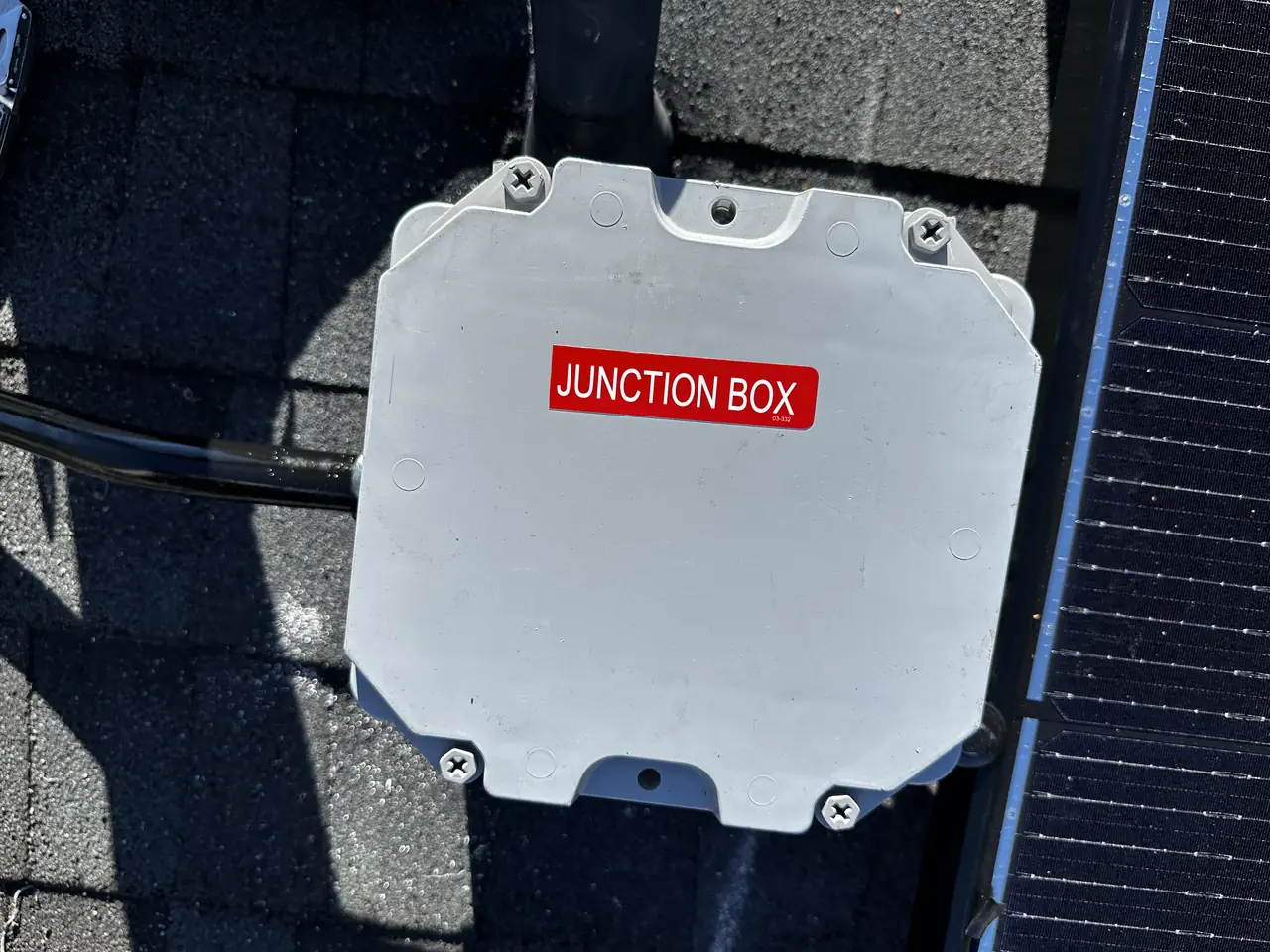 Roof junction box with a red label, mounted on shingle beside a module, North Hollywood