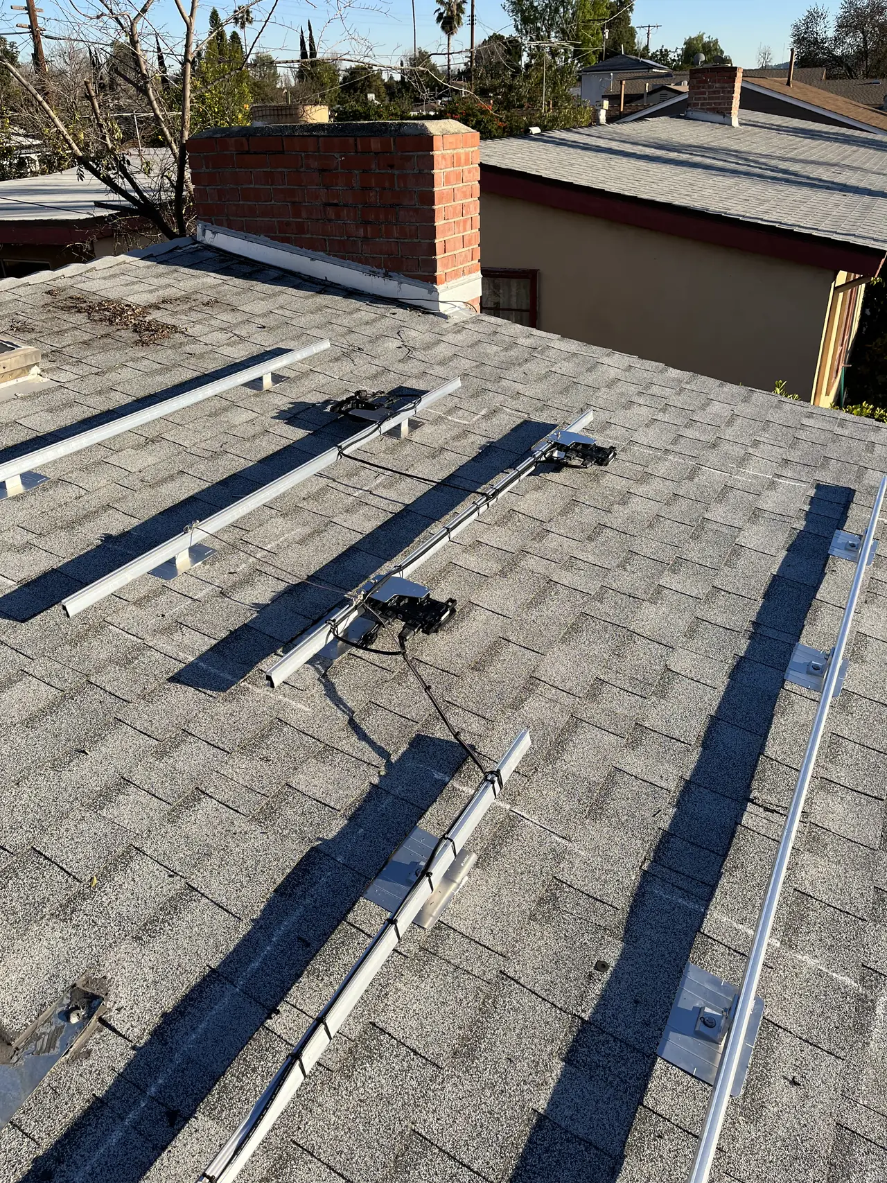Mounting rails laid out in rows across a grey shingle roof, North Hollywood