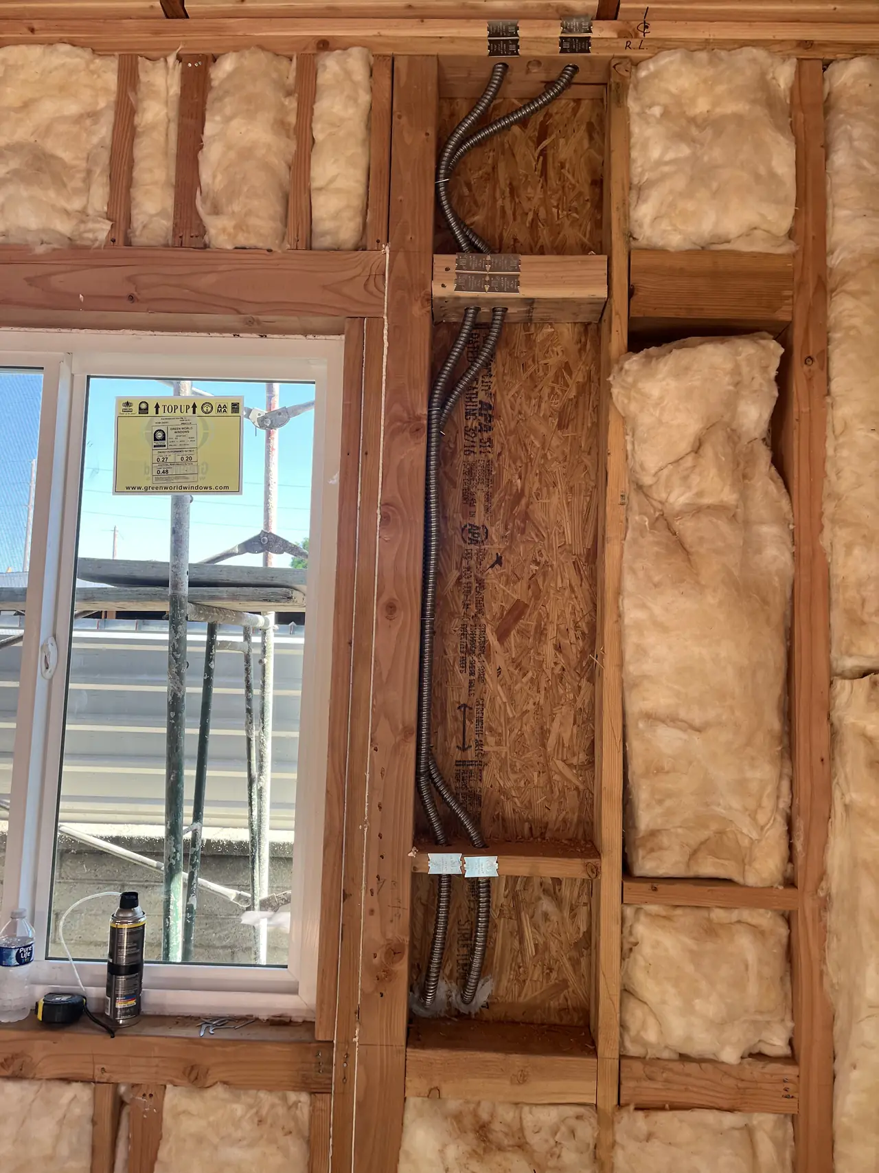 Electrical conduit running through open wall framing beside a new window, North Hollywood
