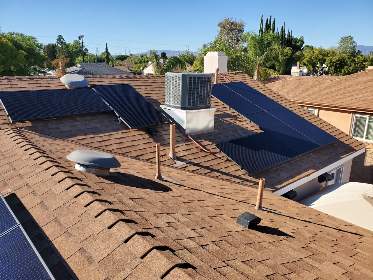 Solar modules on several roof planes with a rooftop air-conditioning condenser and vents between them, North Hollywood
