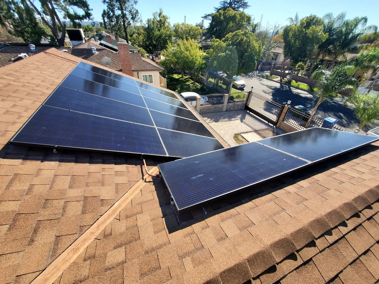 Solar arrays across several planes of a brown shingle roof with the neighbourhood beyond, North Hollywood