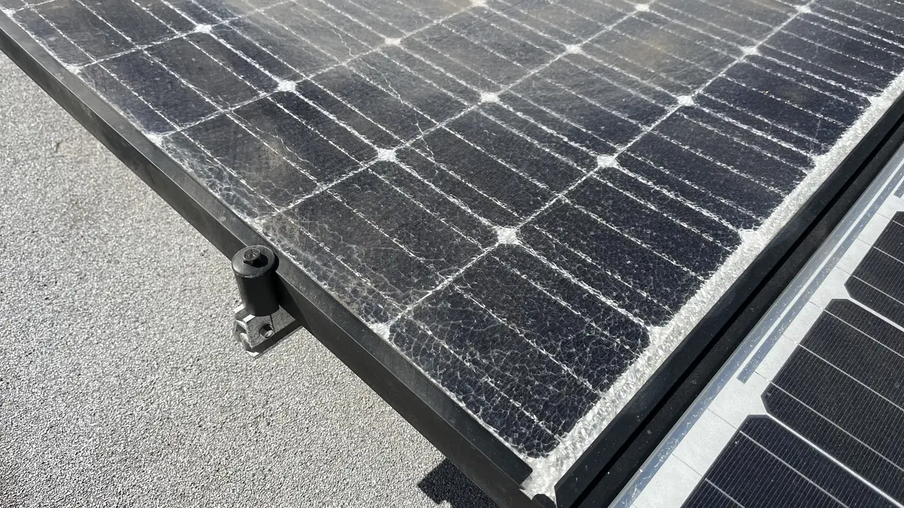 Edge of a solar array on a flat roof showing a mounting foot and undamaged modules, North Hollywood
