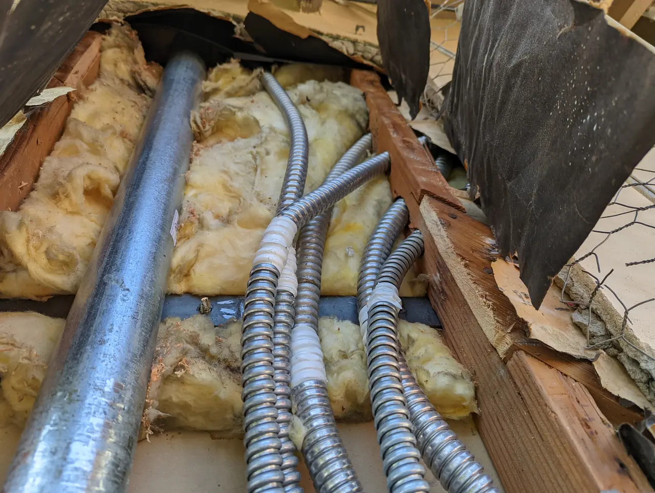 Flexible conduit runs through insulation in an opened wall cavity, North Hollywood