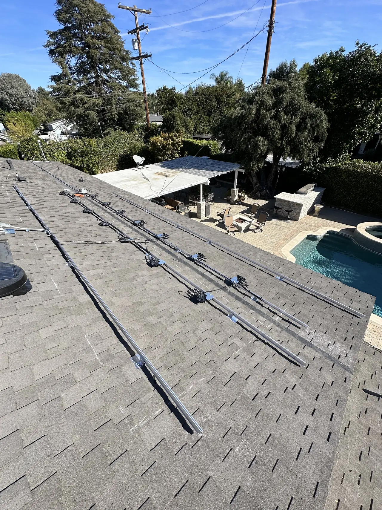 Mounting rails laid out on a shingle roof beside a pool, Northridge