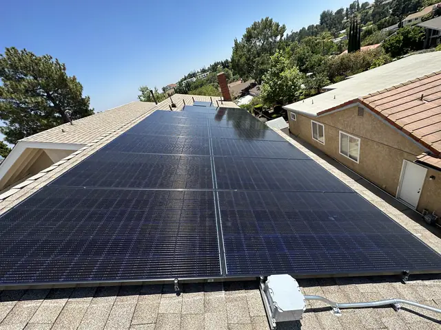 Solar modules on a composition shingle roof with tile-roofed houses behind, Northridge