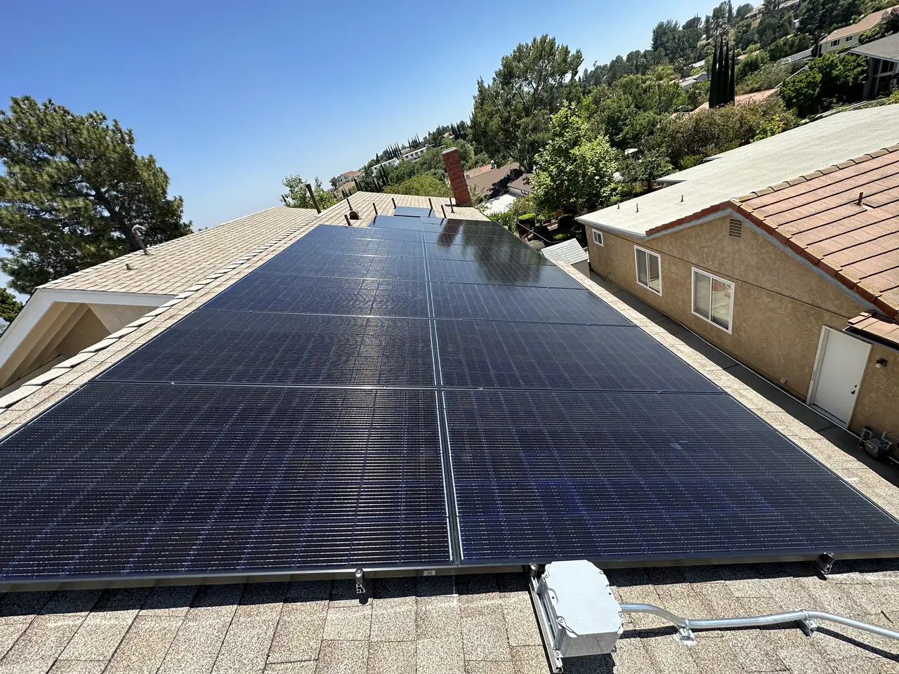 Solar modules on a composition shingle roof with tile-roofed houses behind, Northridge