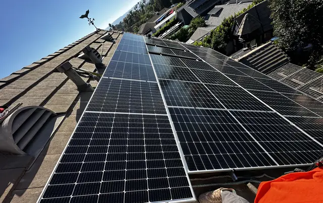 Large solar array across a flat concrete tile roof above a canyon, Northridge