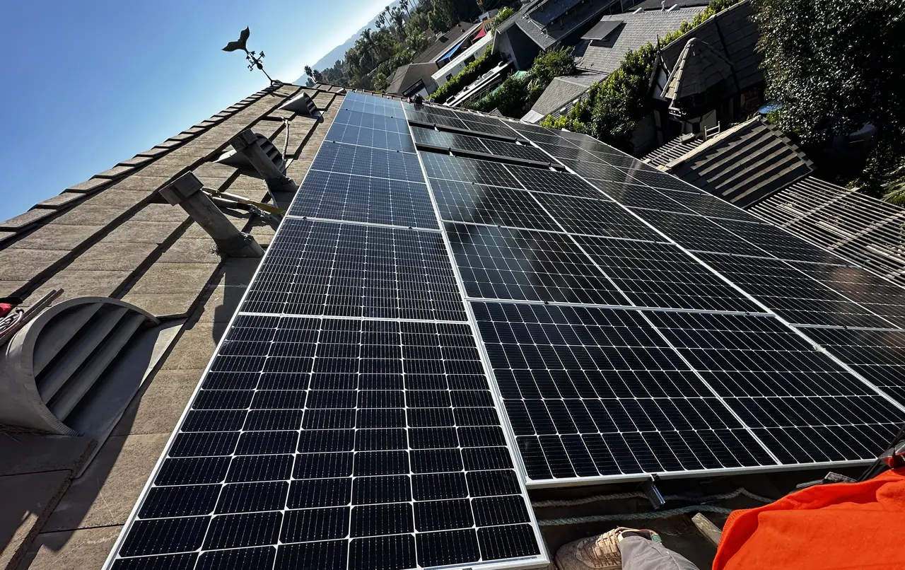 Large solar array across a flat concrete tile roof above a canyon, Northridge