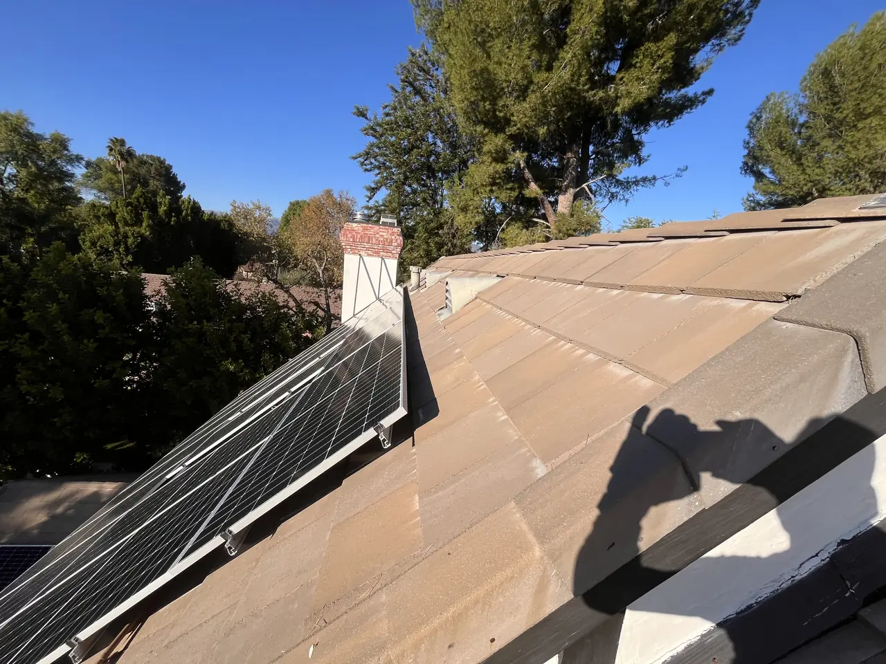 Finished solar array along a tile ridge with trees beyond, Northridge
