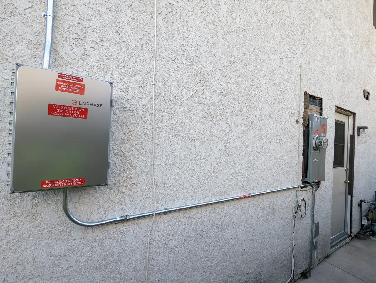 New meter and main enclosure set into an exterior wall with conduit run, Northridge