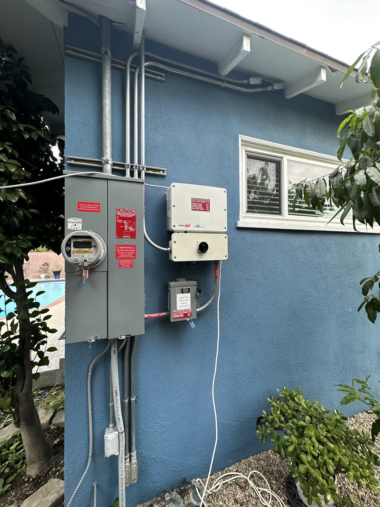 Inverter, meter enclosure and disconnect on the side of a blue stucco house, Northridge