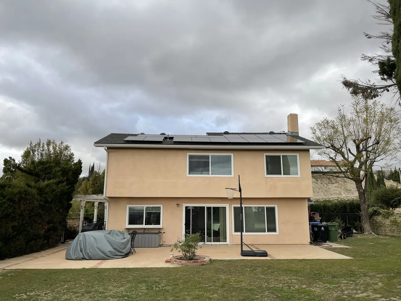 Two-storey house with a solar array on the roof seen from the garden, Northridge