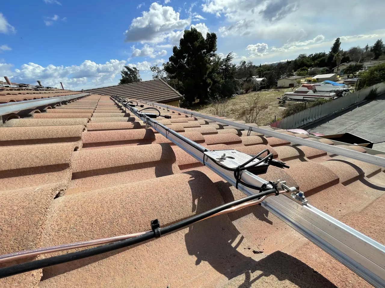 A tile hook and mounting rail fixed to a barrel tile roof, photographed close up, Pacoima, Los Angeles