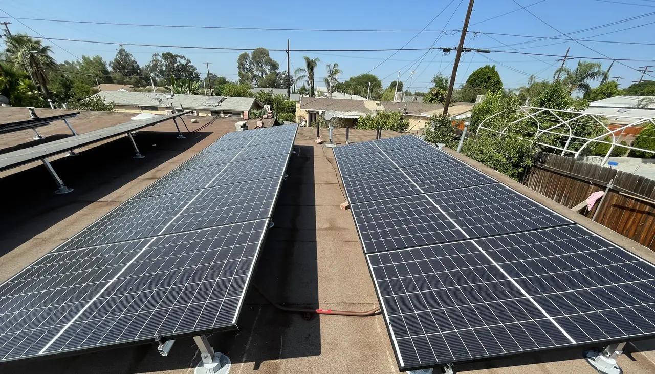 Two rows of tilted solar modules with a clear walkway between them on a low-slope roof, Pacoima, Los Angeles