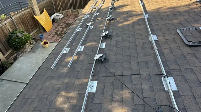 Mounting rails and flashed standoffs set out across a bare composition shingle roof before any modules, Pacoima, Los Angeles