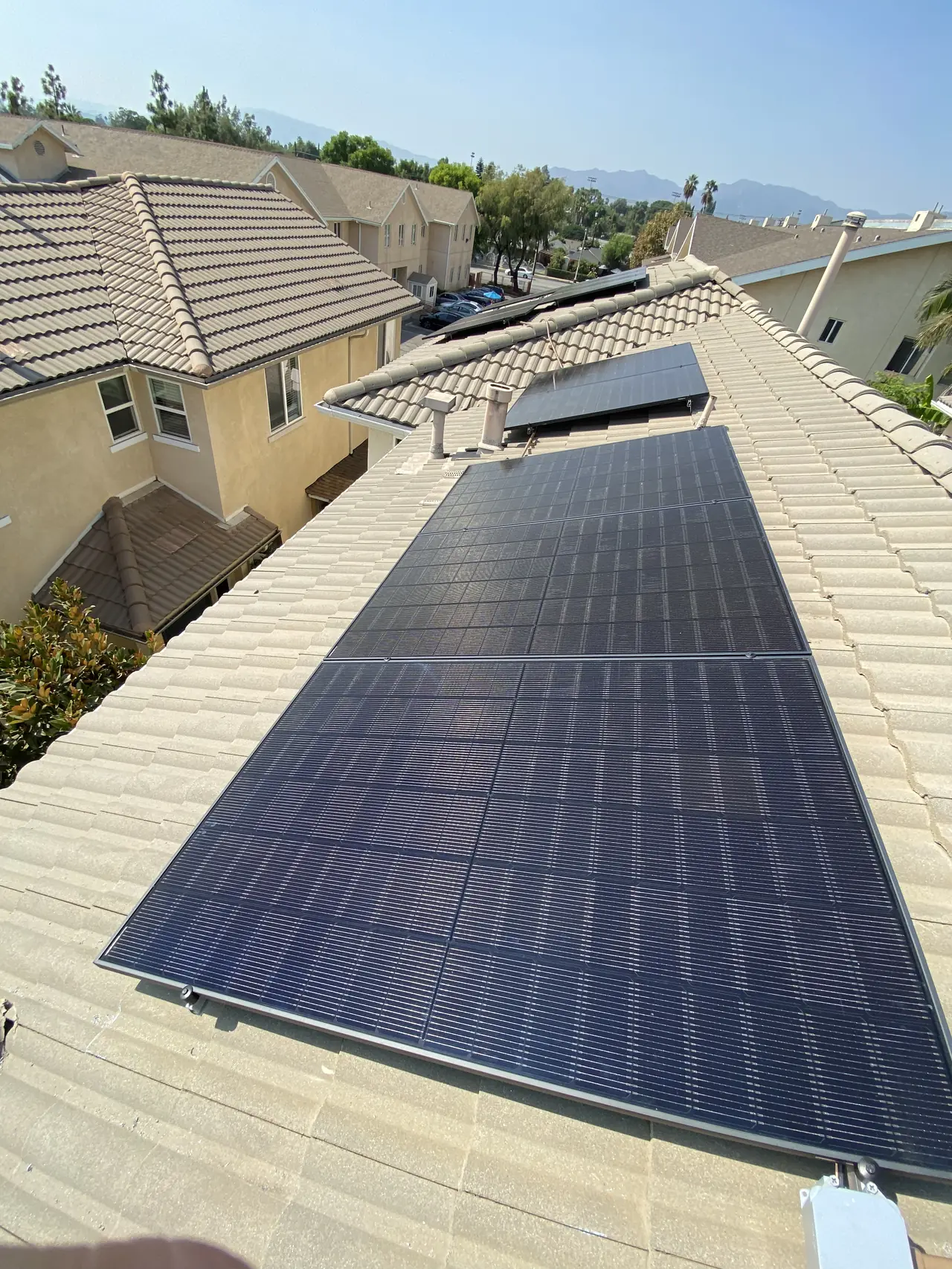 A solar array running down a concrete tile plane with a block of similar rooftops beyond, Pacoima, Los Angeles