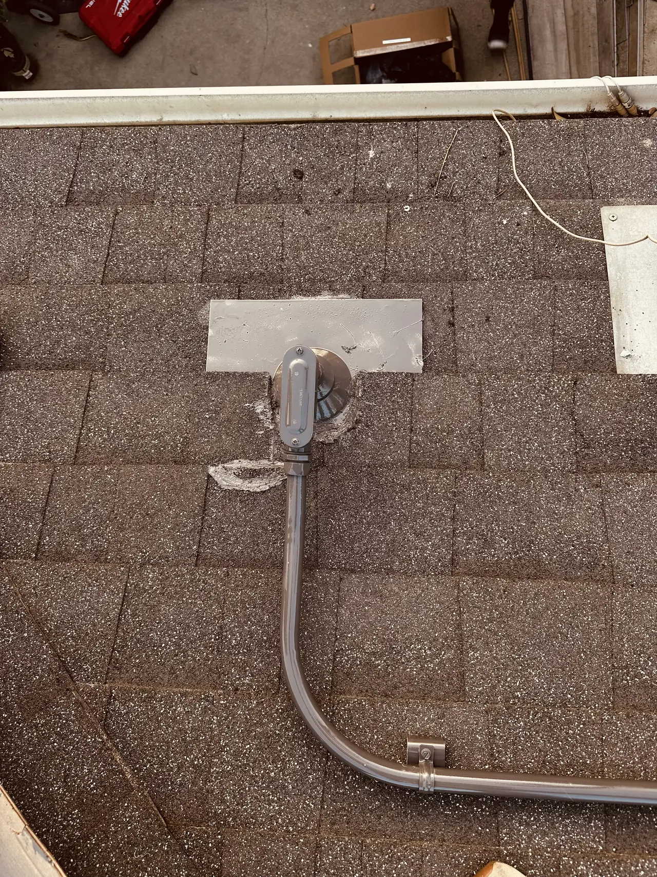 A conduit penetration through composition shingle with a metal flashing plate slipped under the course above it, Panorama City