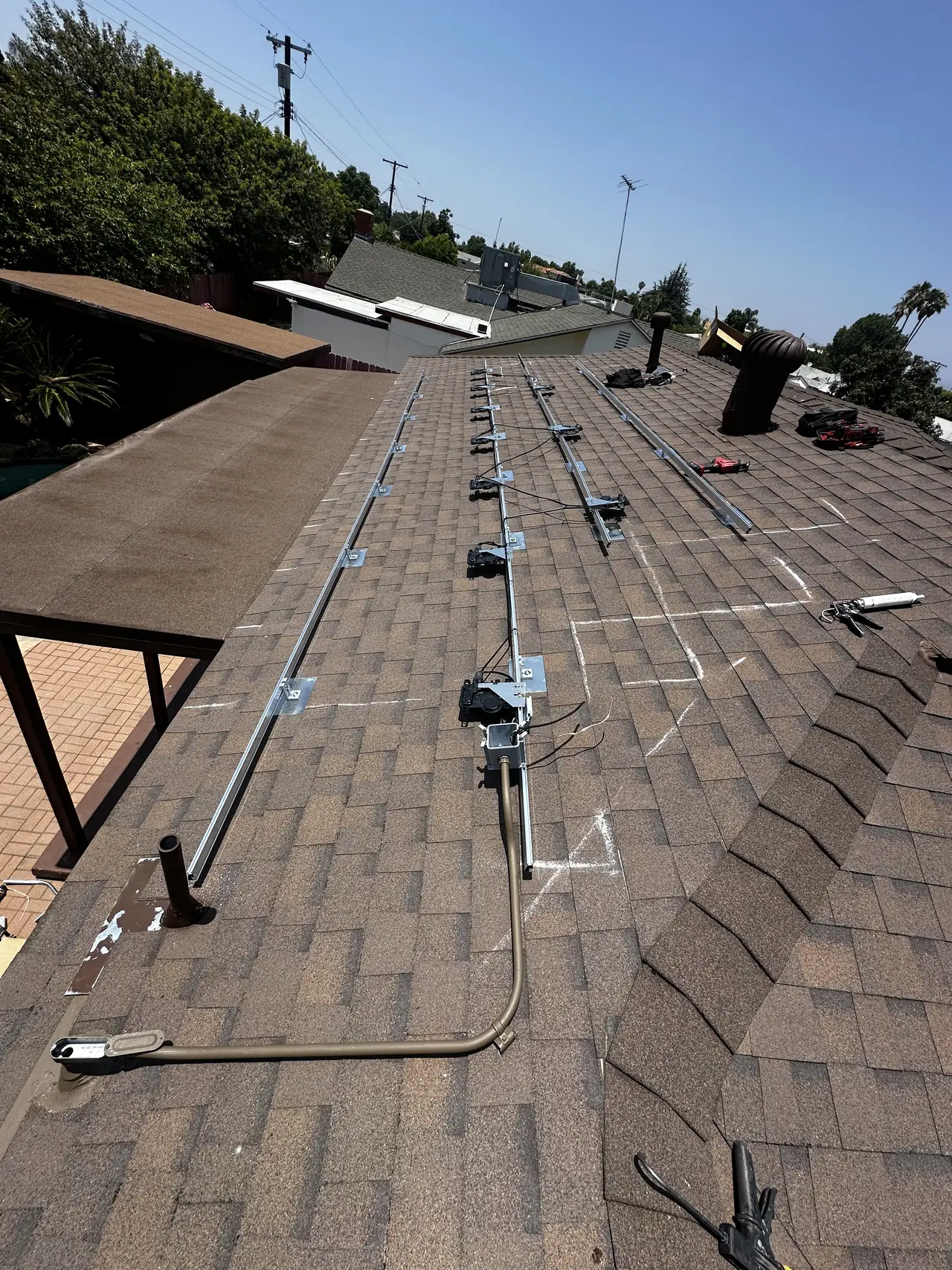 Aluminum rails running the length of the shingle roof with microinverters already mounted along them, Panorama City
