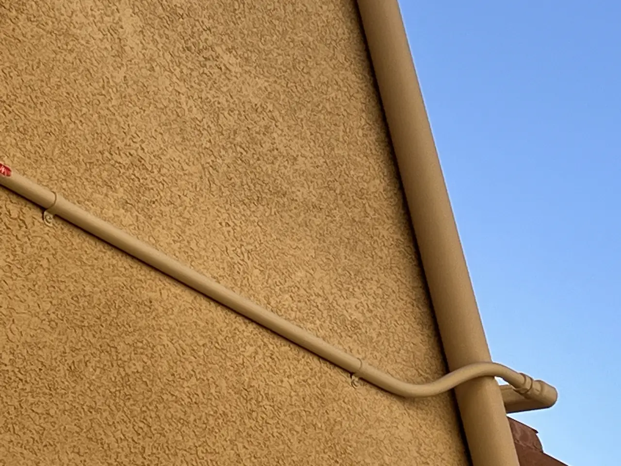 Conduit running down a stucco wall, painted to match the trim, Porter Ranch