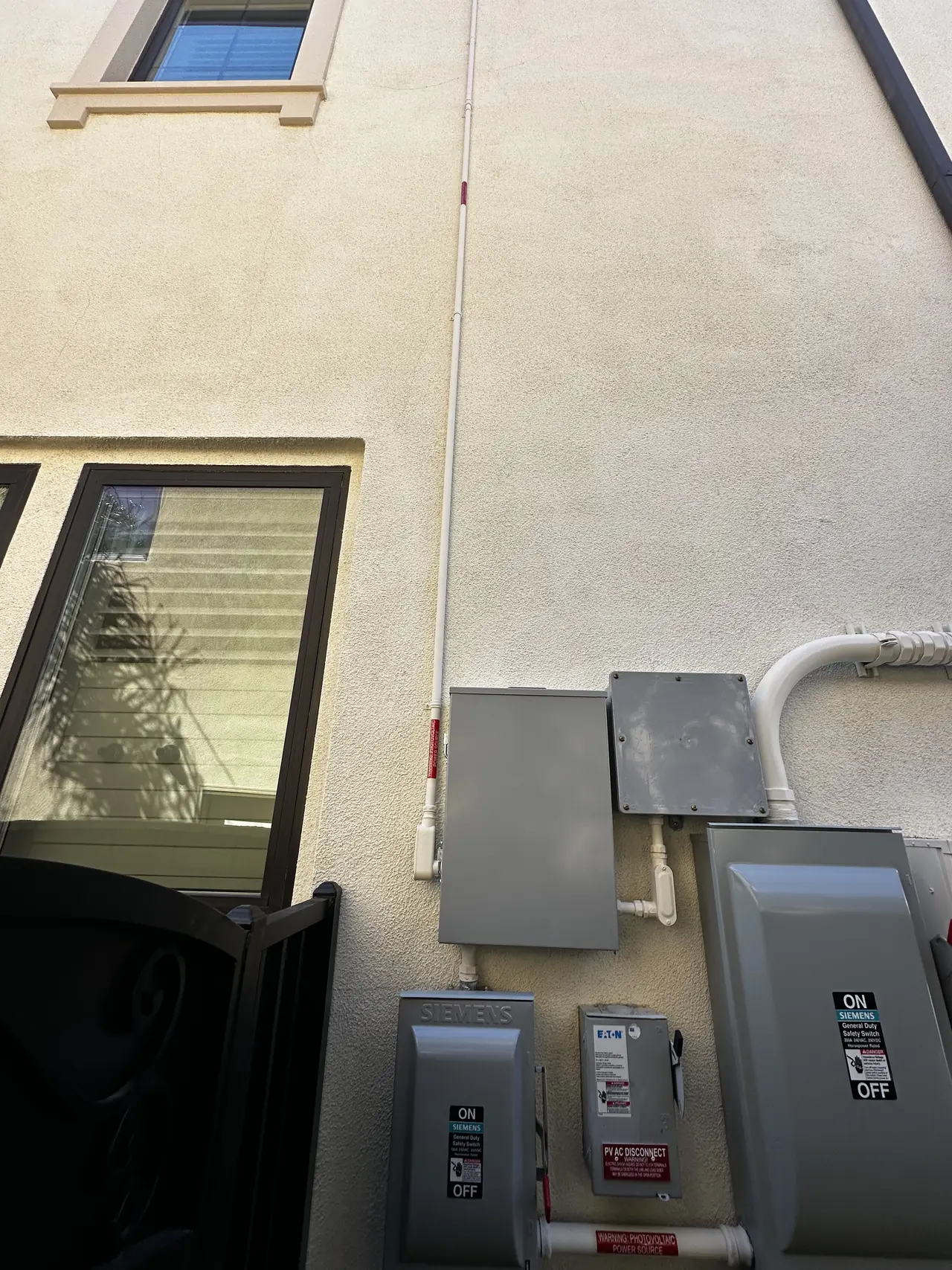 A stucco wall carrying a sub panel and two closed disconnects, Porter Ranch