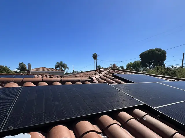 Finished black solar modules on a converted shingle section with original clay barrel tile running alongside the ridge, Reseda