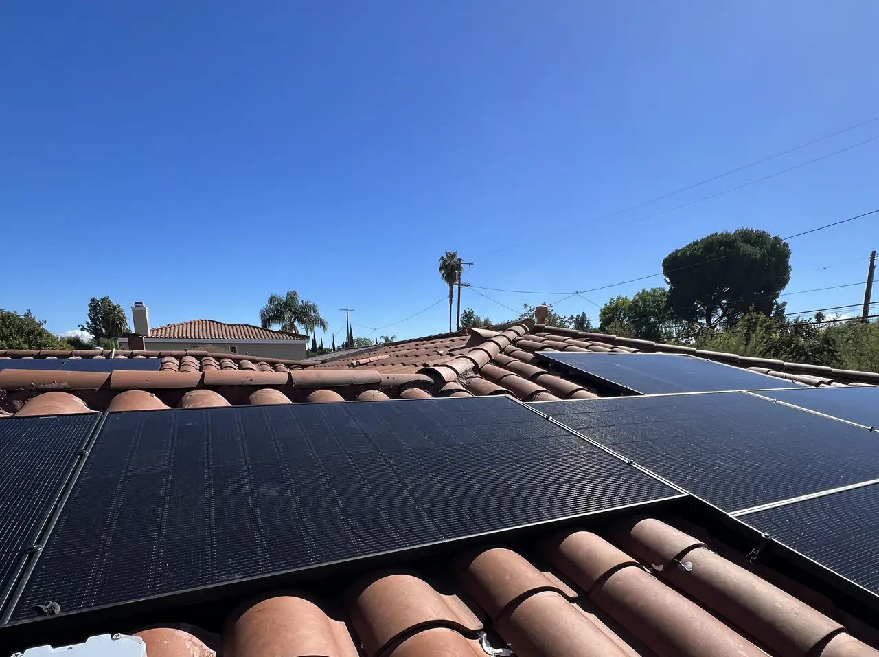 Finished black solar modules on a converted shingle section with original clay barrel tile running alongside the ridge, Reseda