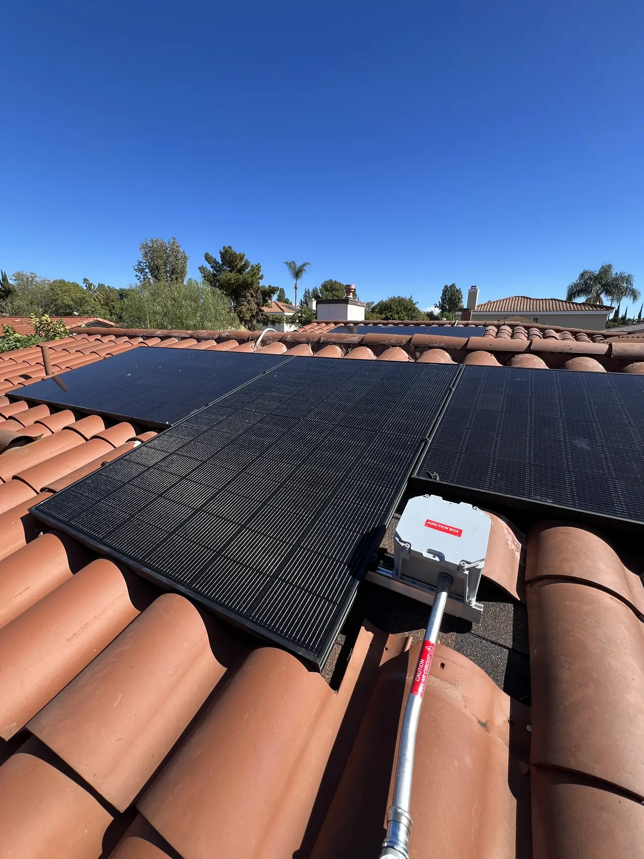 Completed black modules meeting re-laid clay barrel tile along the roof edge, Reseda