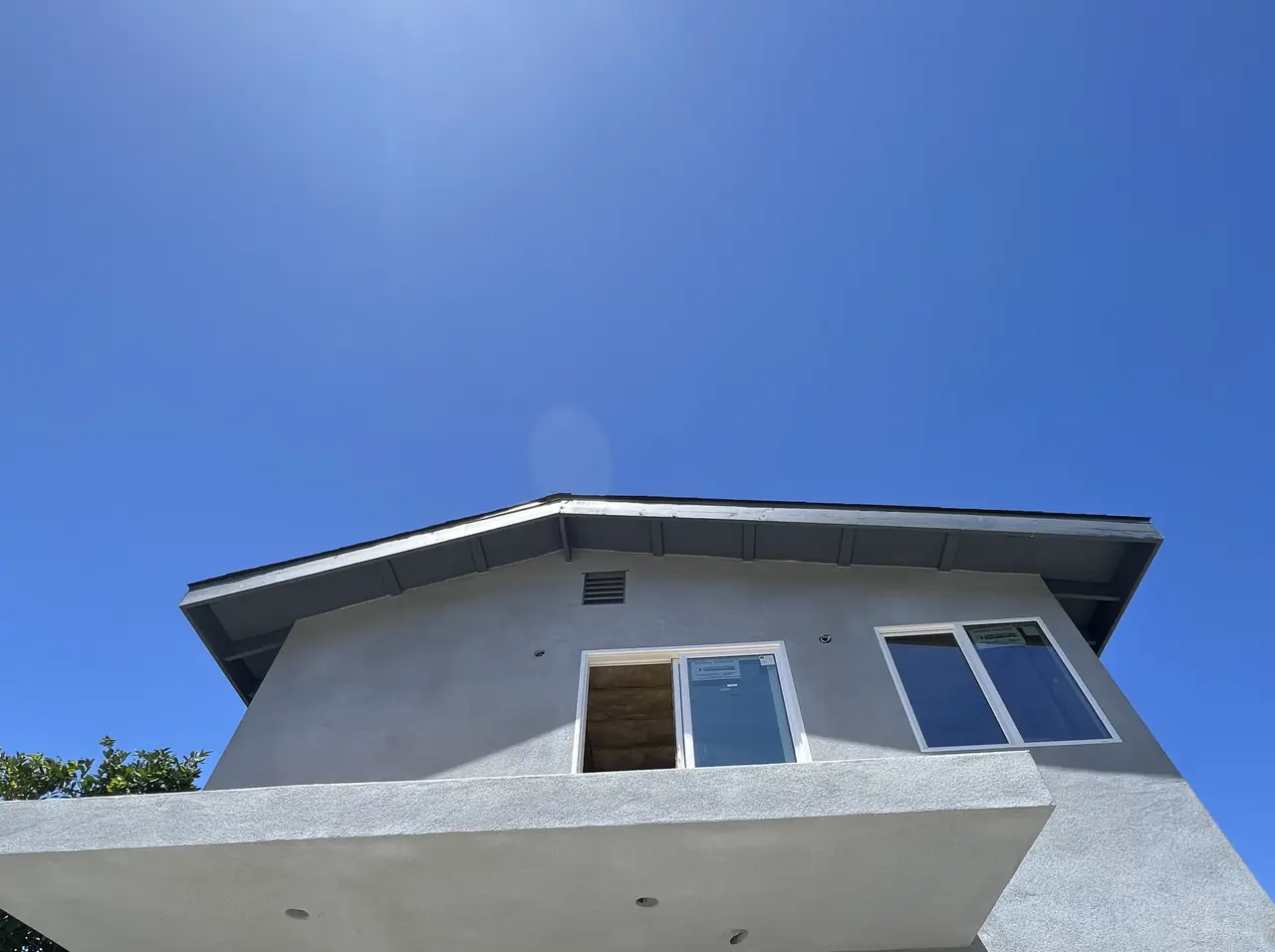 A new two-story stucco accessory dwelling unit photographed from below against a clear sky, Reseda
