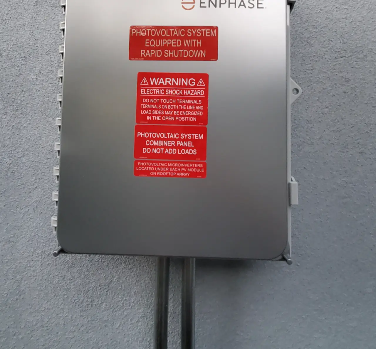 Enphase combiner mounted on the exterior stucco wall of the new unit with rapid shutdown labeling, Reseda