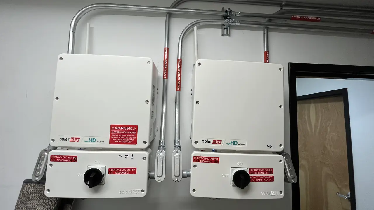 Two SolarEdge HD-Wave inverters mounted side by side on an indoor wall with conduit above them, San Fernando