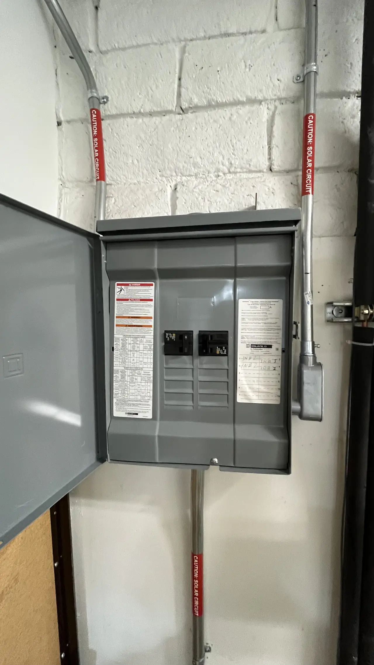 A closed electrical panel with solar circuit labels on the conduit running into it, San Fernando
