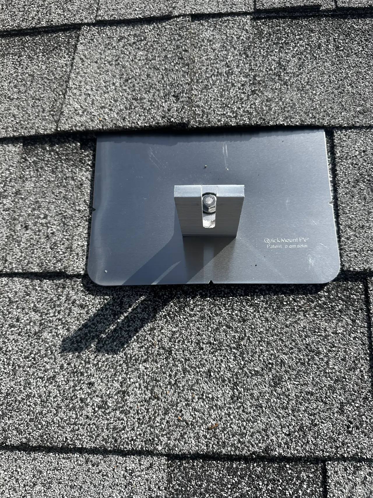 A flashed L-foot solar mount woven into a gray shingle roof course, San Fernando