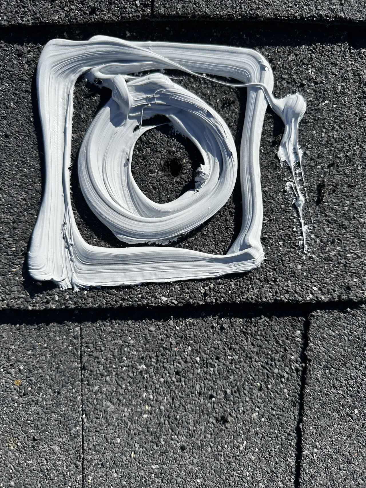 A ring of sealant laid around a drilled mount hole on a dark shingle roof, San Fernando