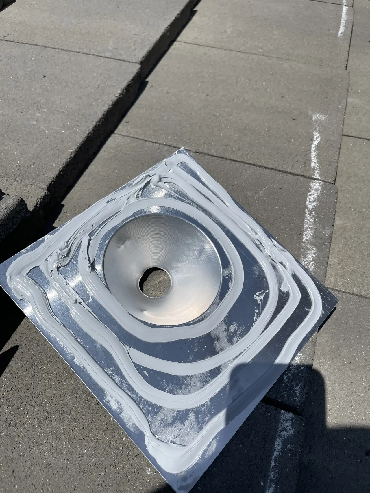 A metal roof flashing for a conduit penetration bedded in rings of sealant on a concrete tile roof, San Fernando
