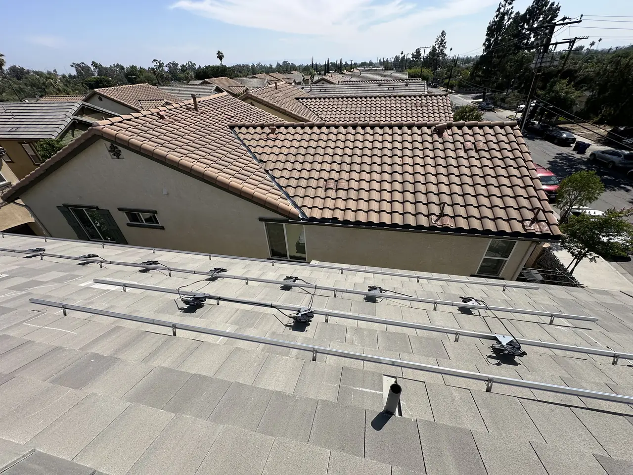 Solar rails with Enphase microinverters mounted above a flat concrete tile roof before the modules, San Fernando