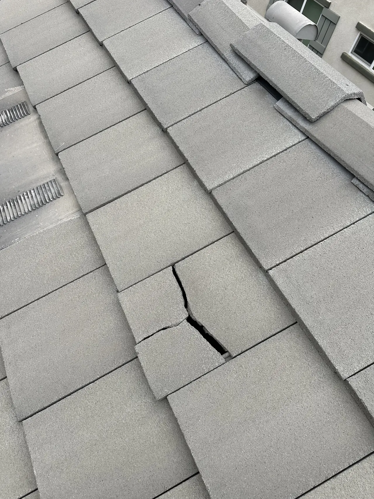 A concrete roof tile split across its face before any solar work, San Fernando