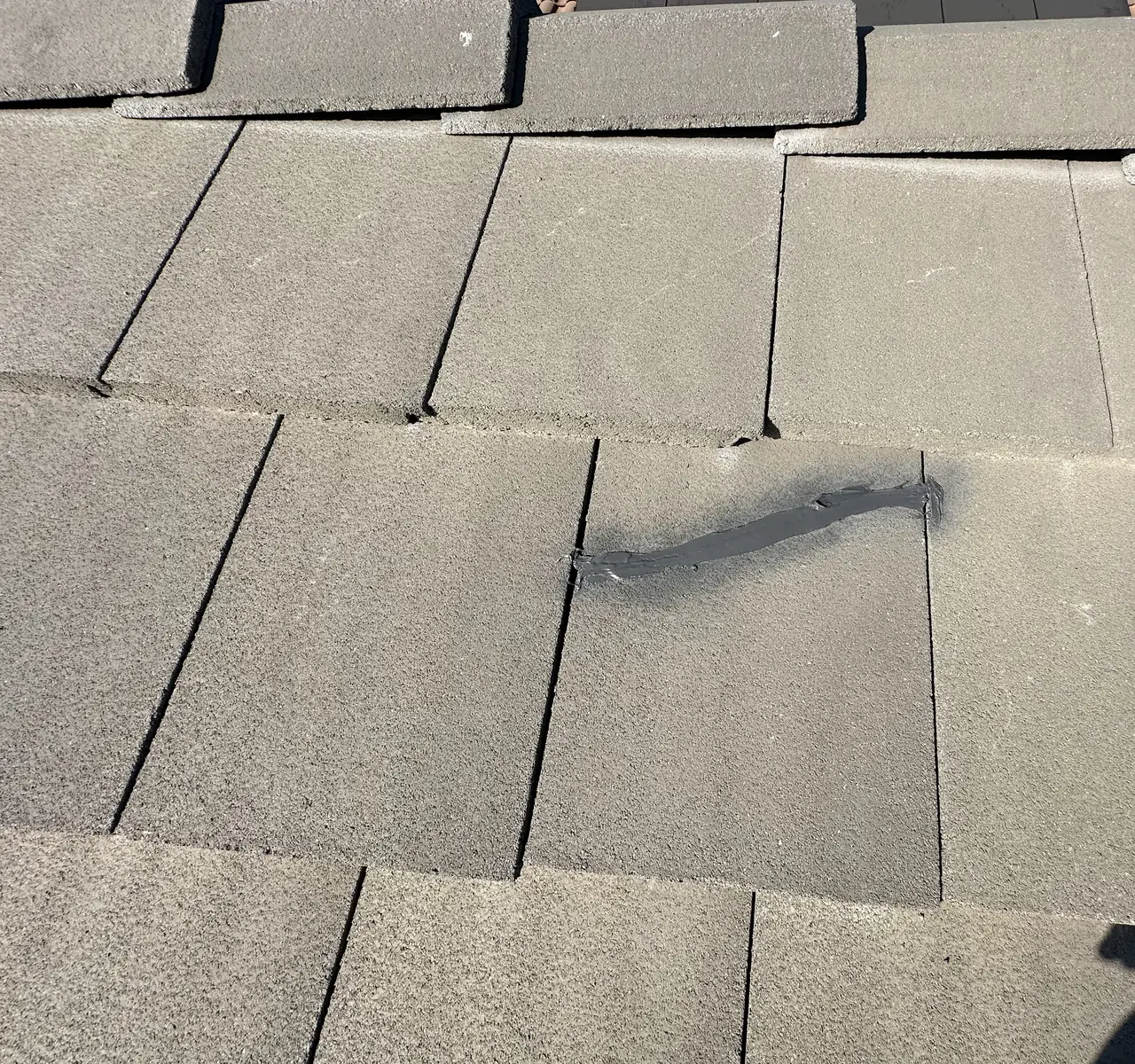 A tile hook fixed on the roof underlayment with sealant spread over its fasteners, concrete tiles below, San Fernando