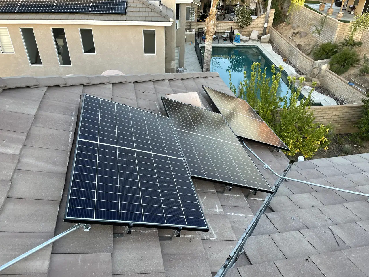 Black modules laid flat across a tile roof above the valley, Santa Clarita