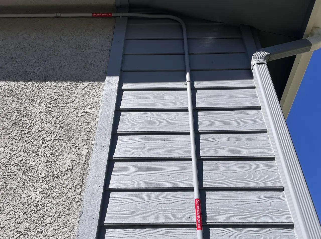 Conduit running down a board-and-batten wall from the roof edge, Santa Clarita