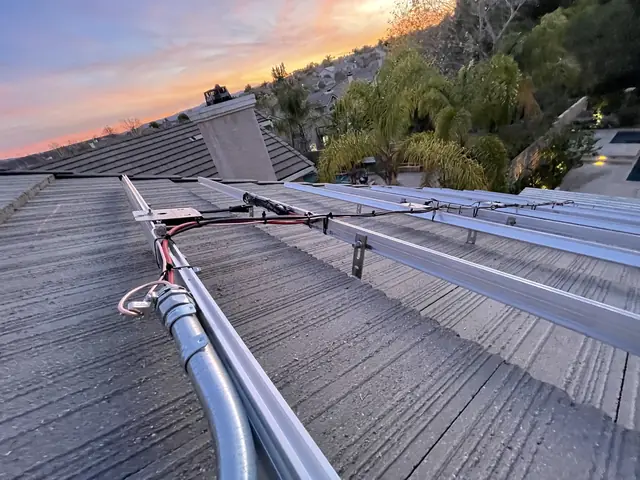 Mounting rails fixed across a concrete tile roof at dusk, Santa Clarita