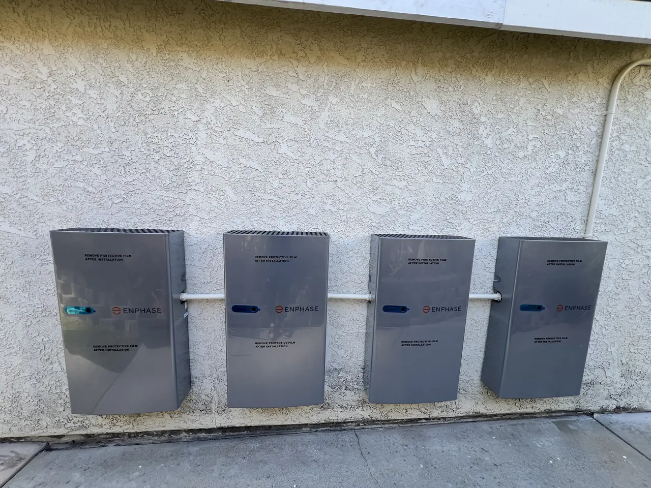 Four battery units mounted in a row on an exterior stucco wall, Santa Clarita