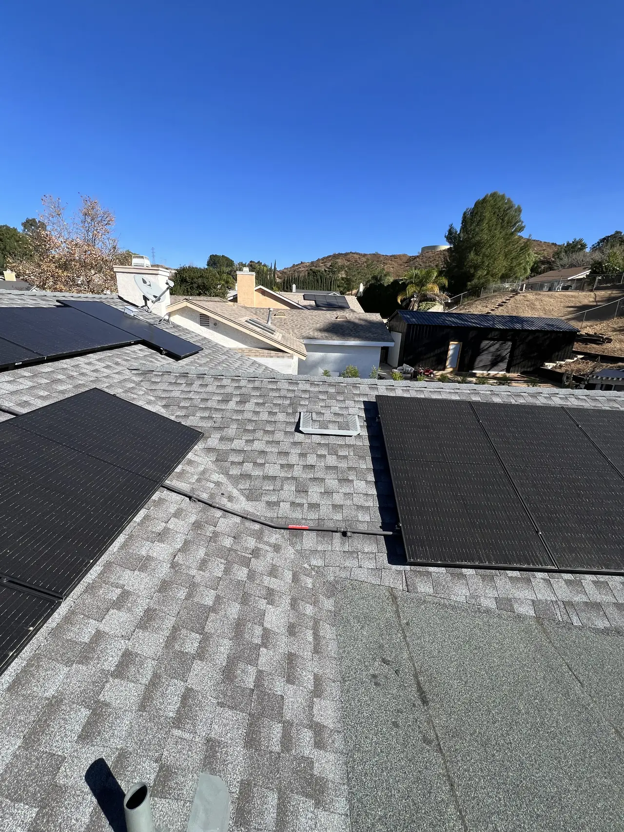 A solar array on a shingle roof with hills behind the house, Santa Clarita