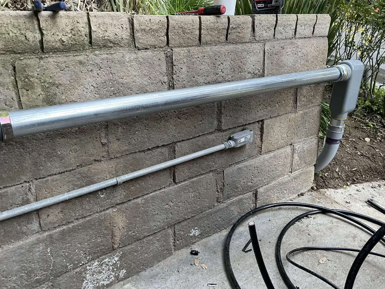 Conduit running along a block retaining wall from the array toward the house, Santa Clarita