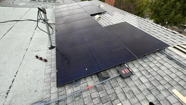 A solar array on a composition-shingle roof with trees beyond it, Santa Clarita