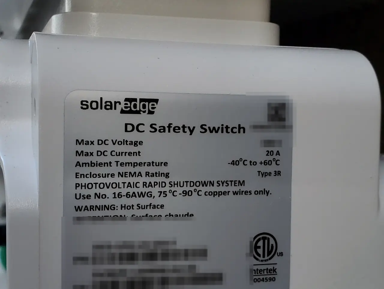 A closed direct-current safety switch below a string inverter on a stucco wall, Santa Clarita
