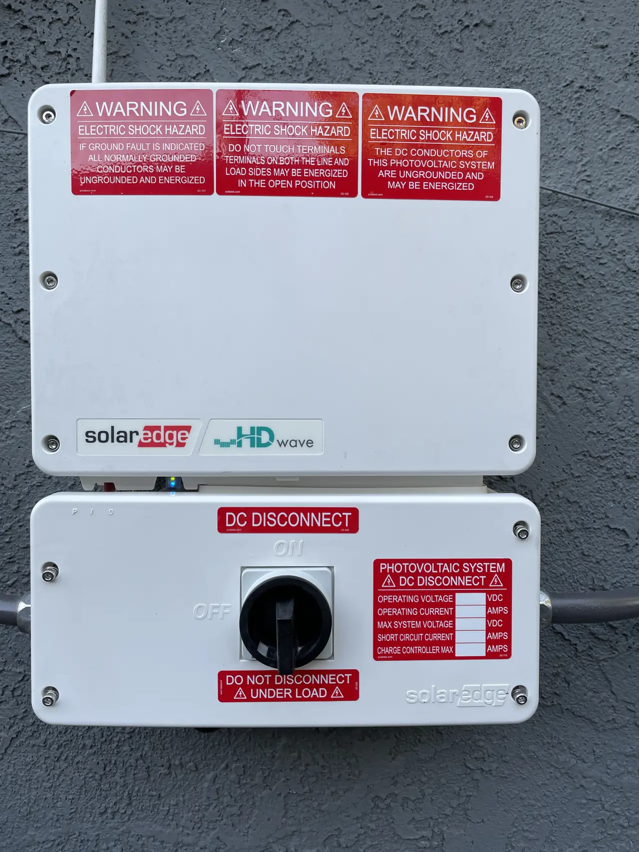 A closed SolarEdge string inverter mounted on an exterior wall, Santa Clarita